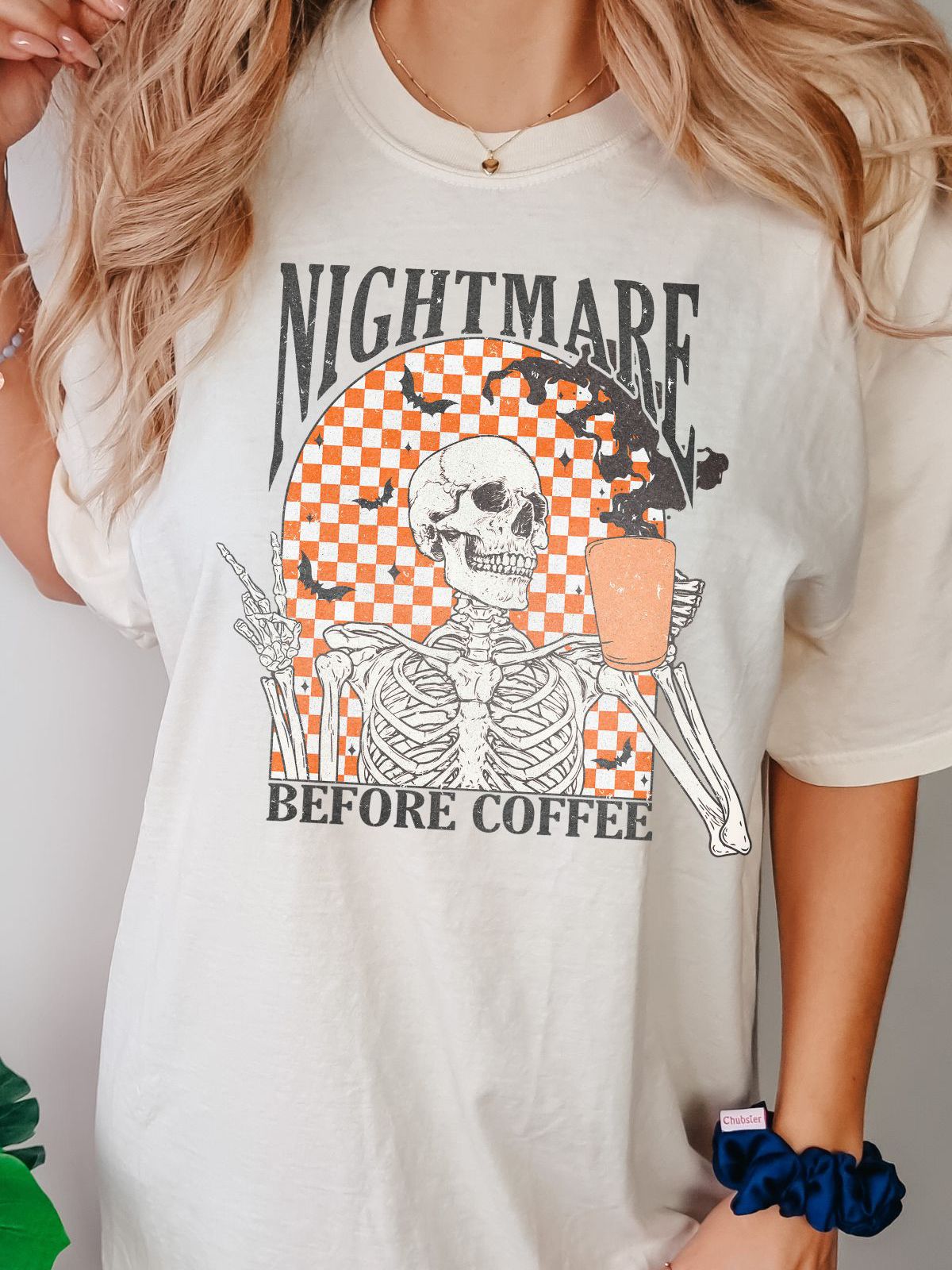 Skeleton with checked background holding coffee titled Nightmare Before Coffee