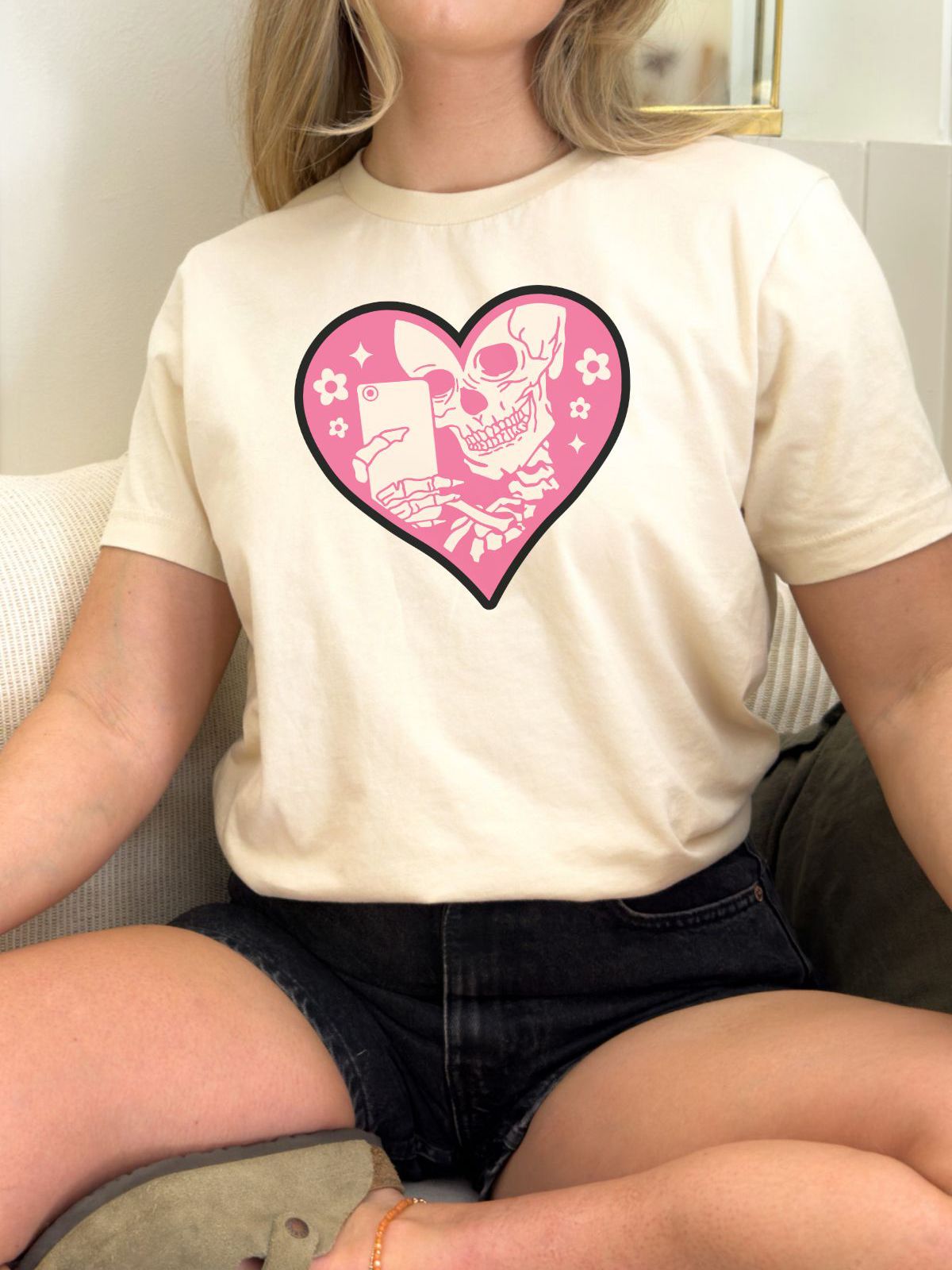 woman wearing a beige t-shirt with pink skeleton heart design