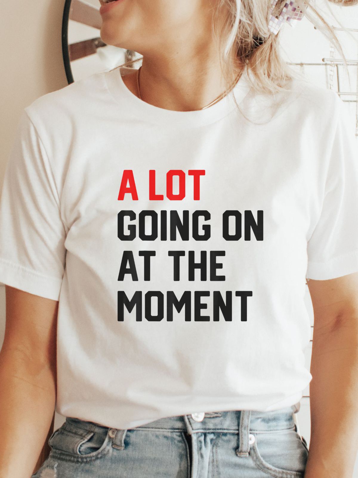 Woman wearing white t-shirt with A Lot Going On At The Moment text