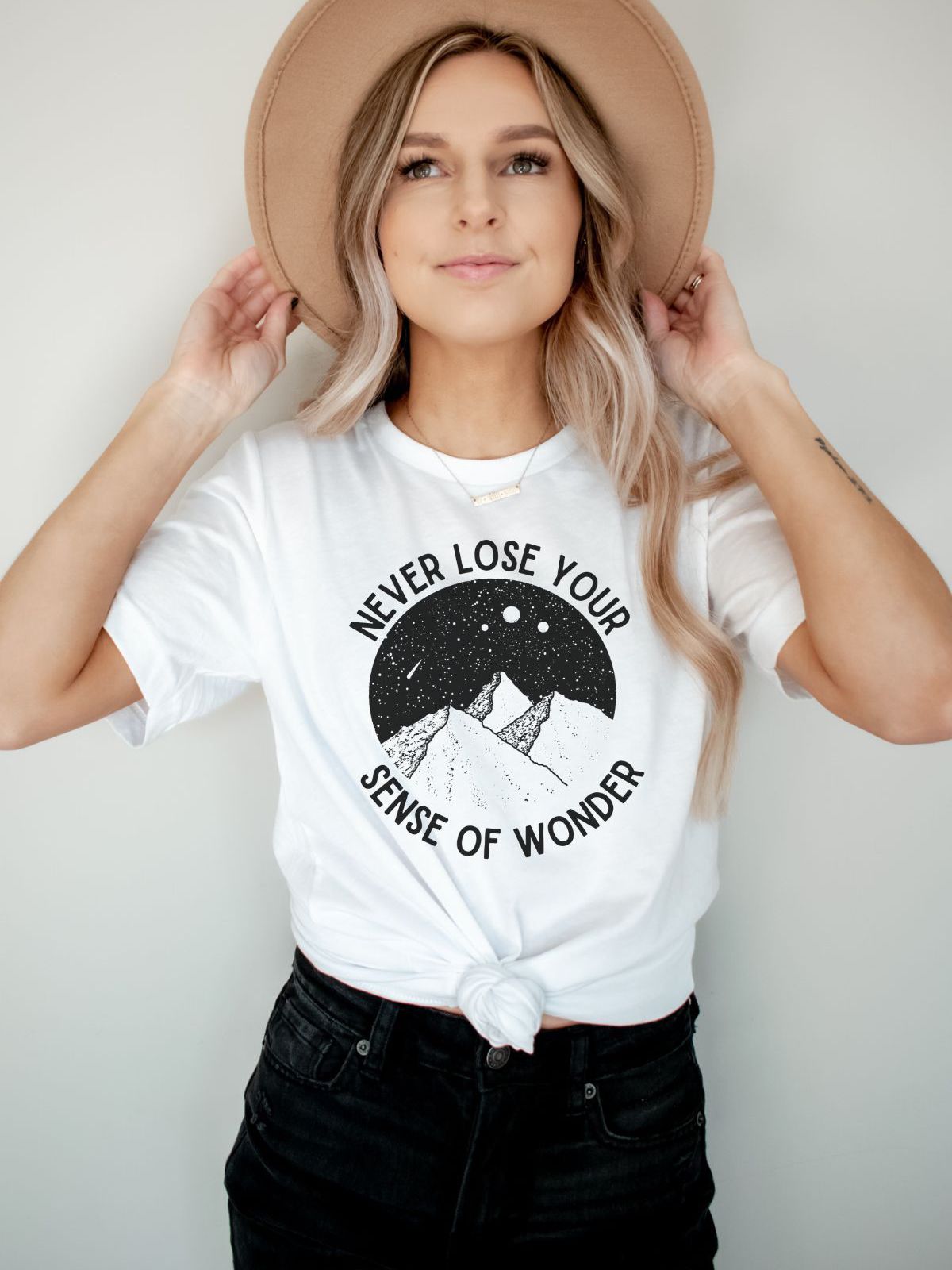 Woman wearing a white t-shirt with sense of wonder graphic