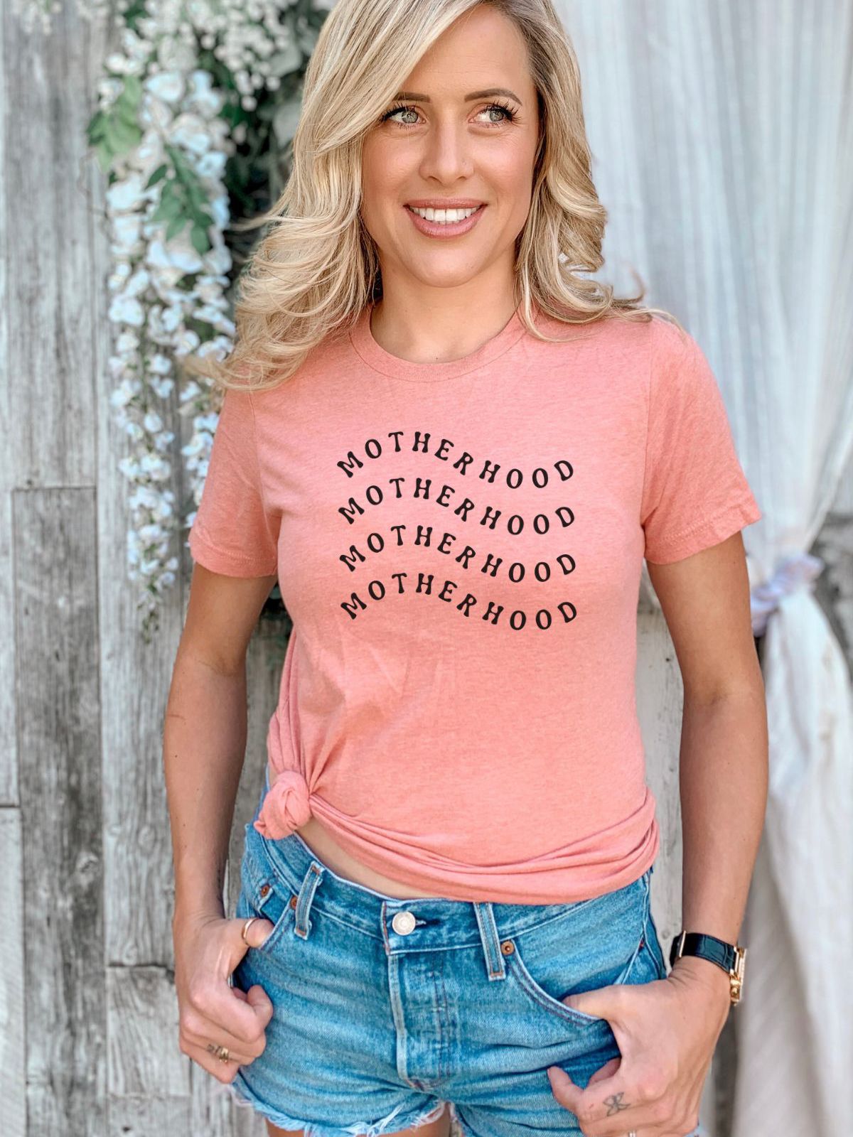 woman wearing a pink motherhood t-shirt and denim shorts