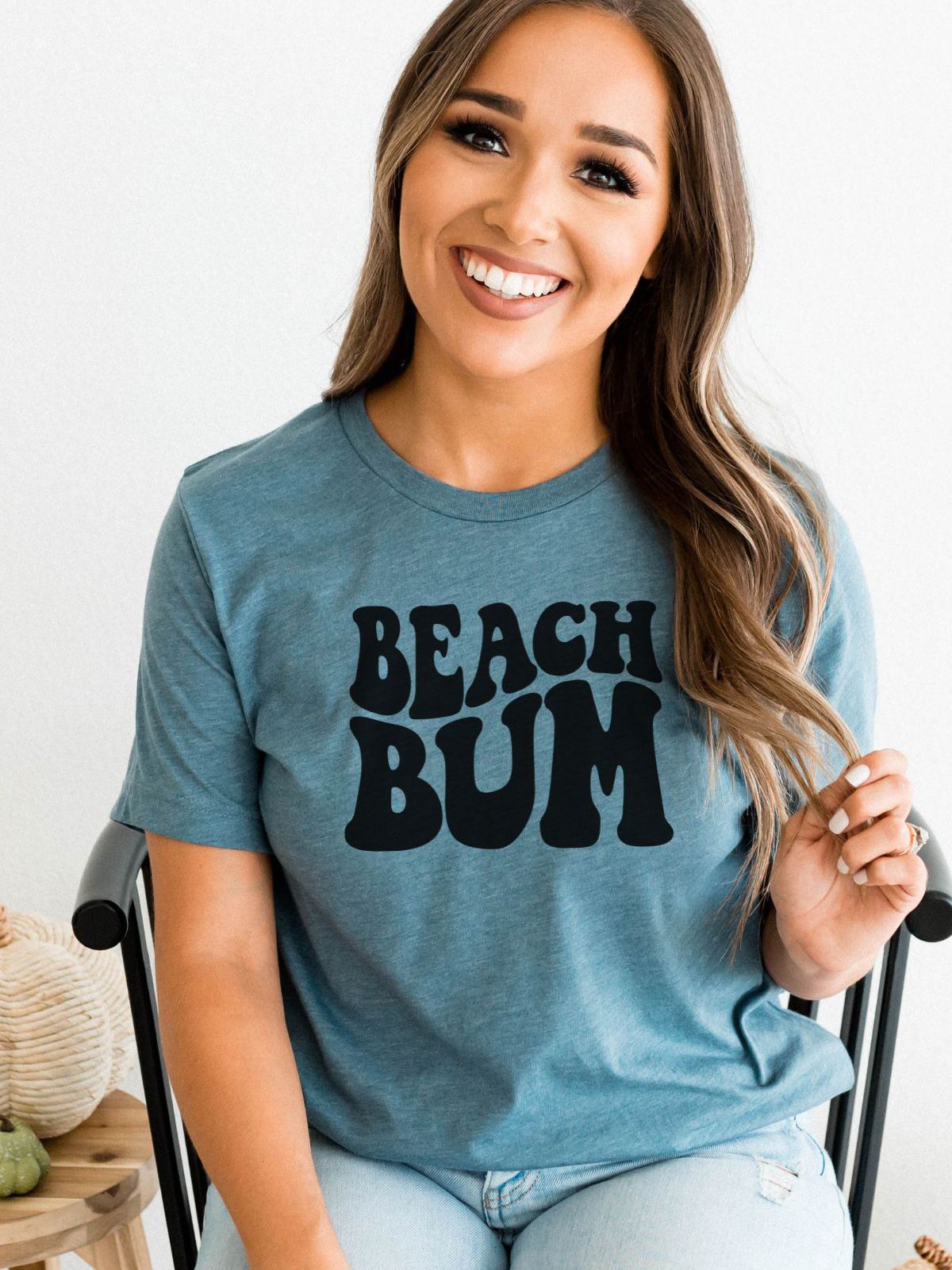 woman wearing a blue beach bum t-shirt sitting on a chair