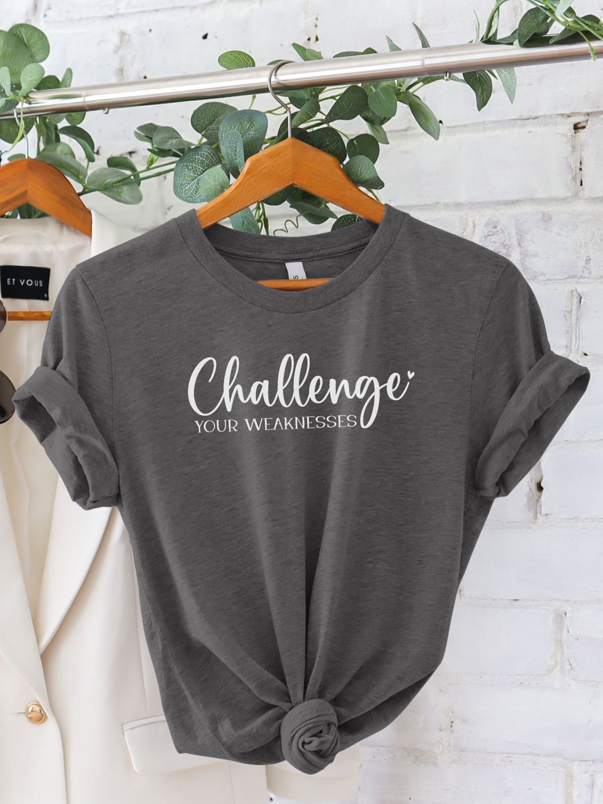 Gray t-shirt with 'Challenge Your Weaknesses' text on hanger