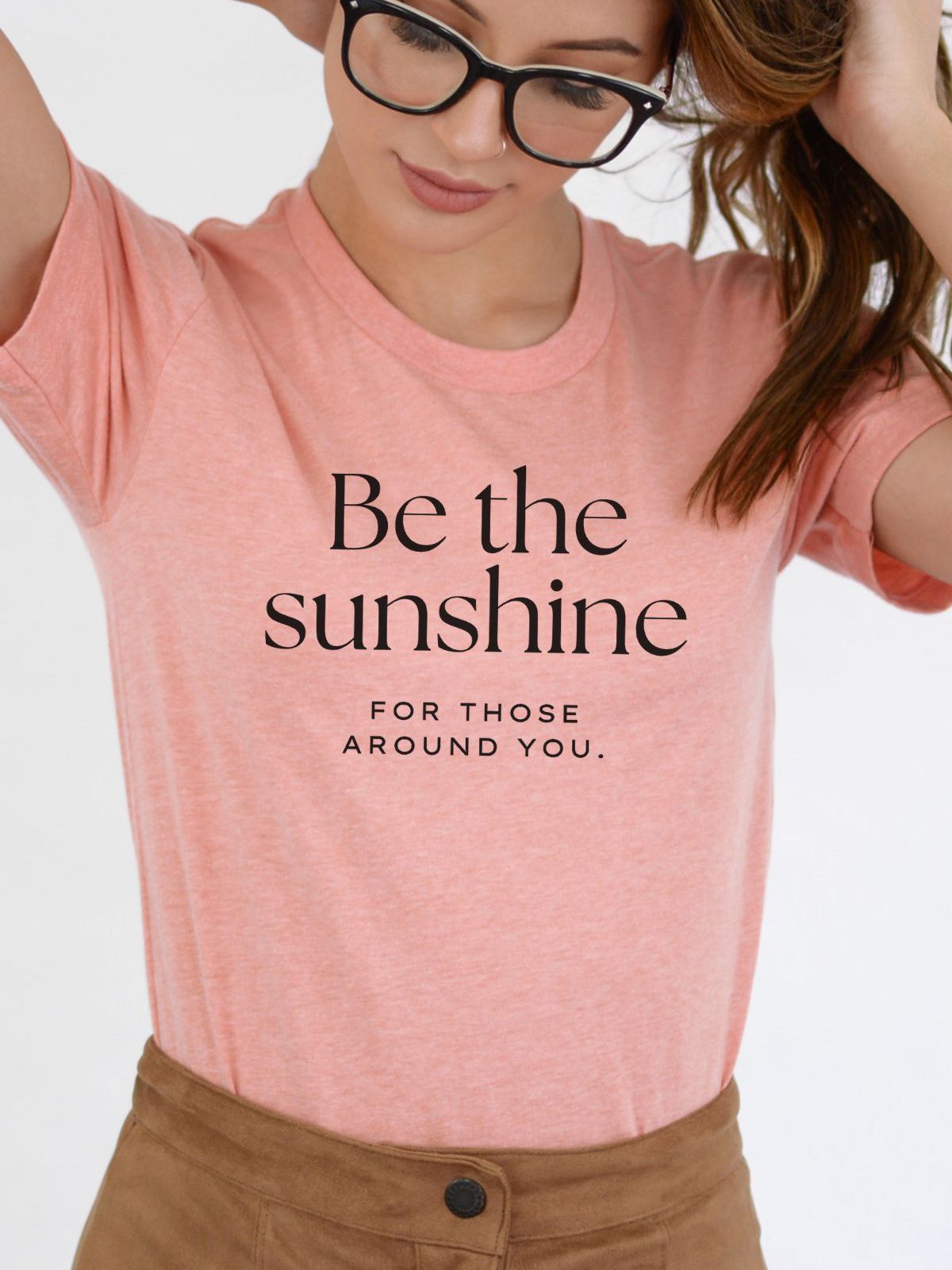 Woman wearing a pink t-shirt with Be the Sunshine text