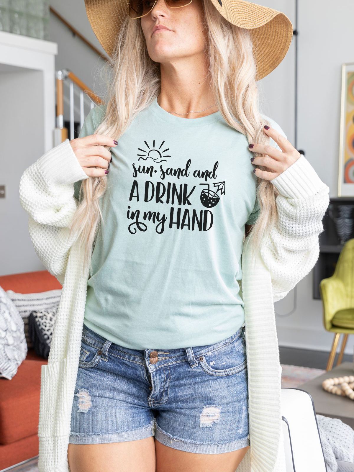 woman wearing summer themed t-shirt with text sun sand and a drink in my hand