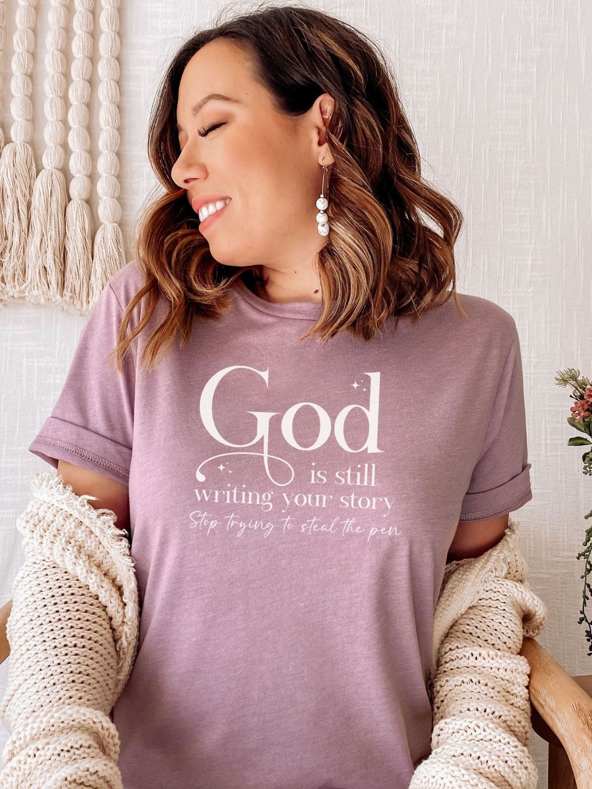 woman wearing a purple t-shirt with text God is still writing your story