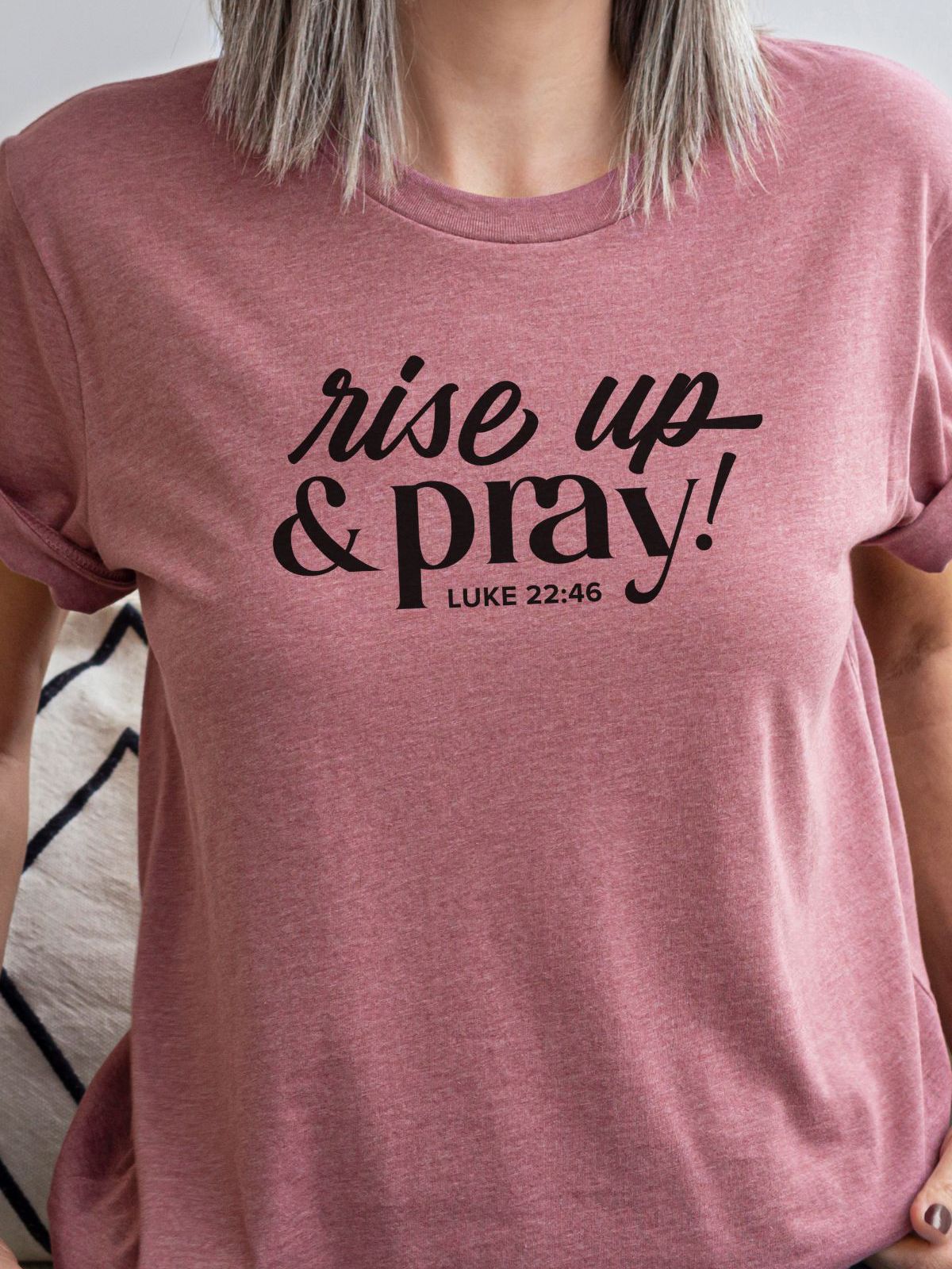 woman wearing a pink t-shirt with rise up and pray text