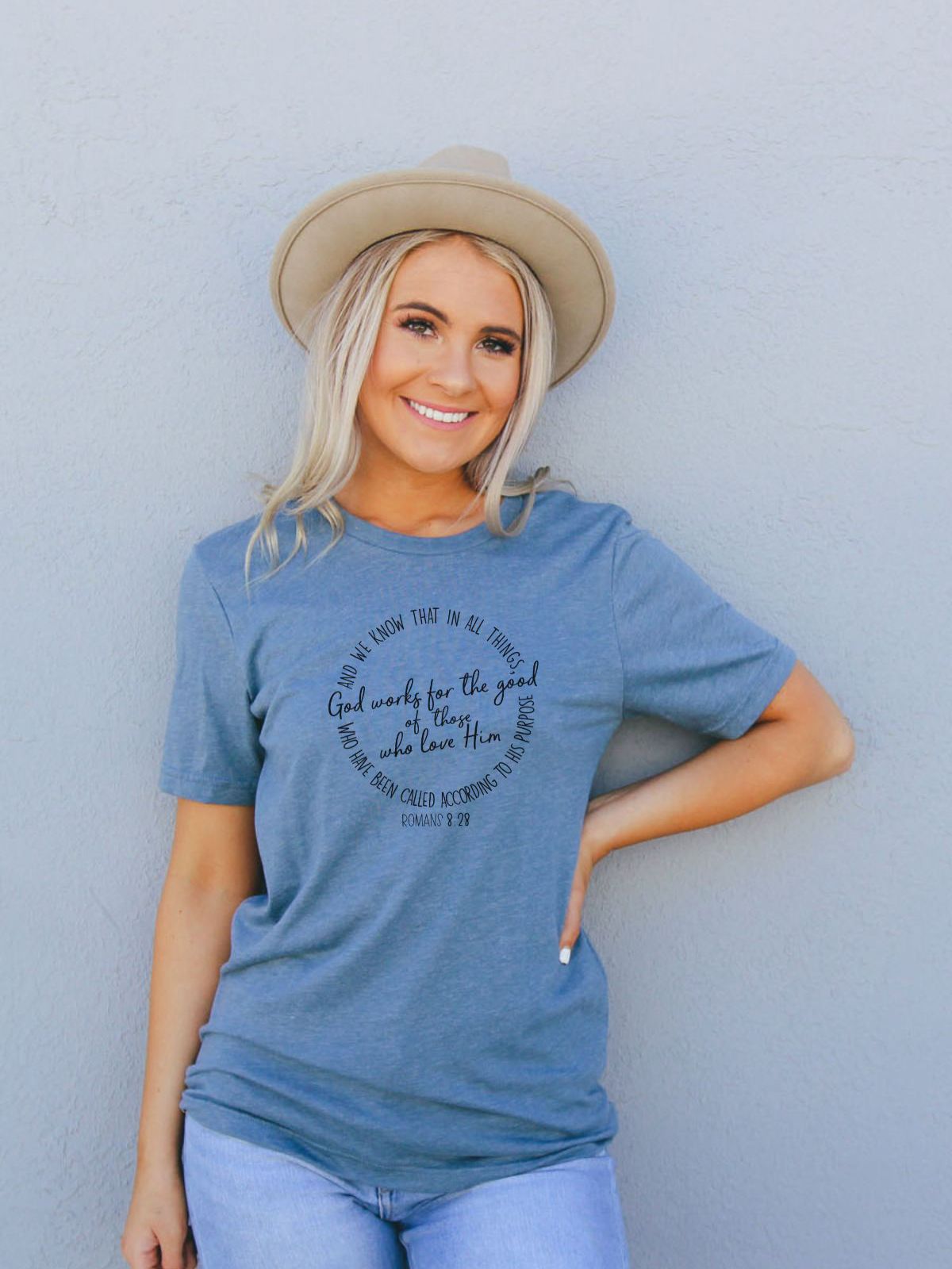 woman wearing a blue t-shirt with romans 8 28 text design