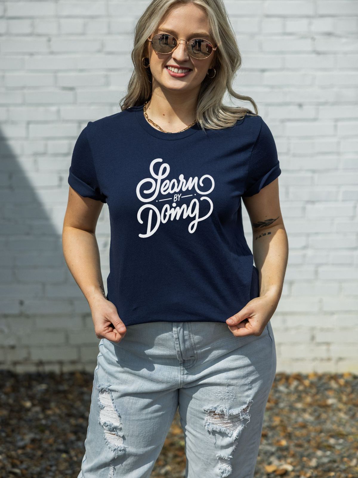 woman wearing a navy blue t-shirt with learn by doing text