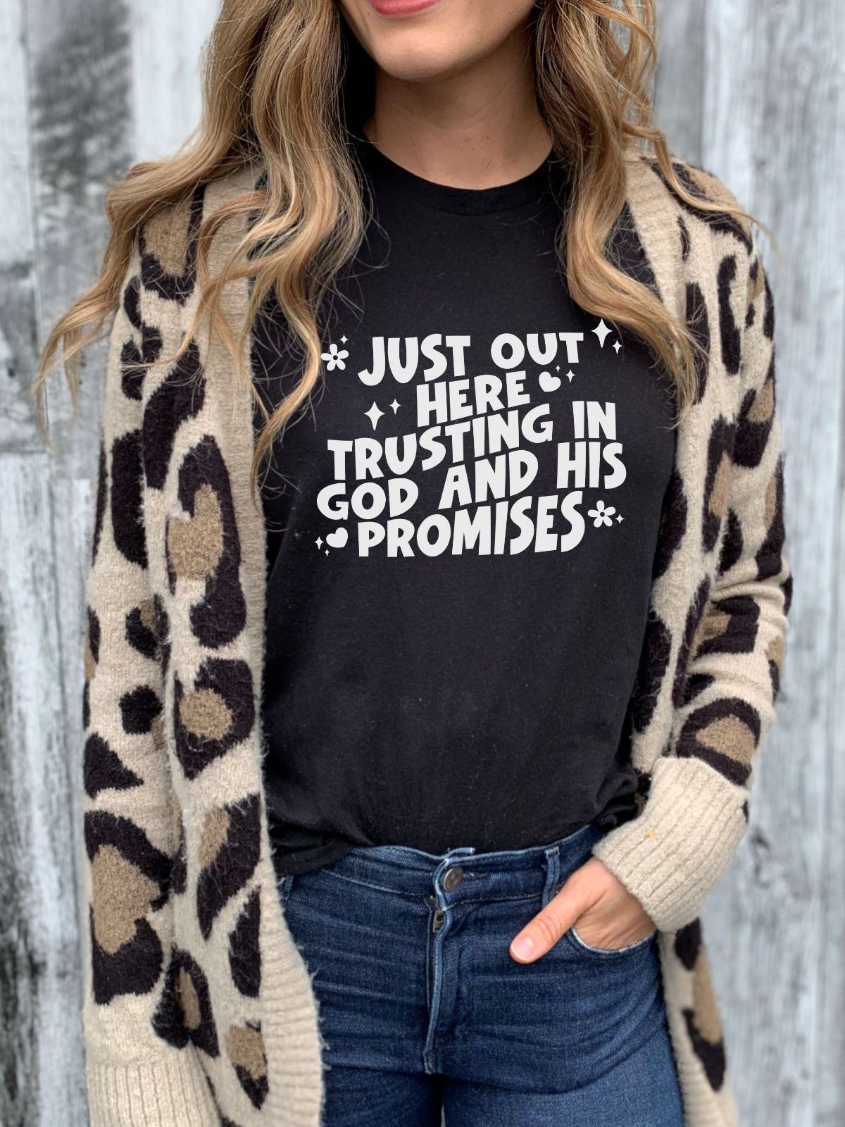 Woman wearing black t-shirt with 'Just Out Here Trusting in God and His Promises' text