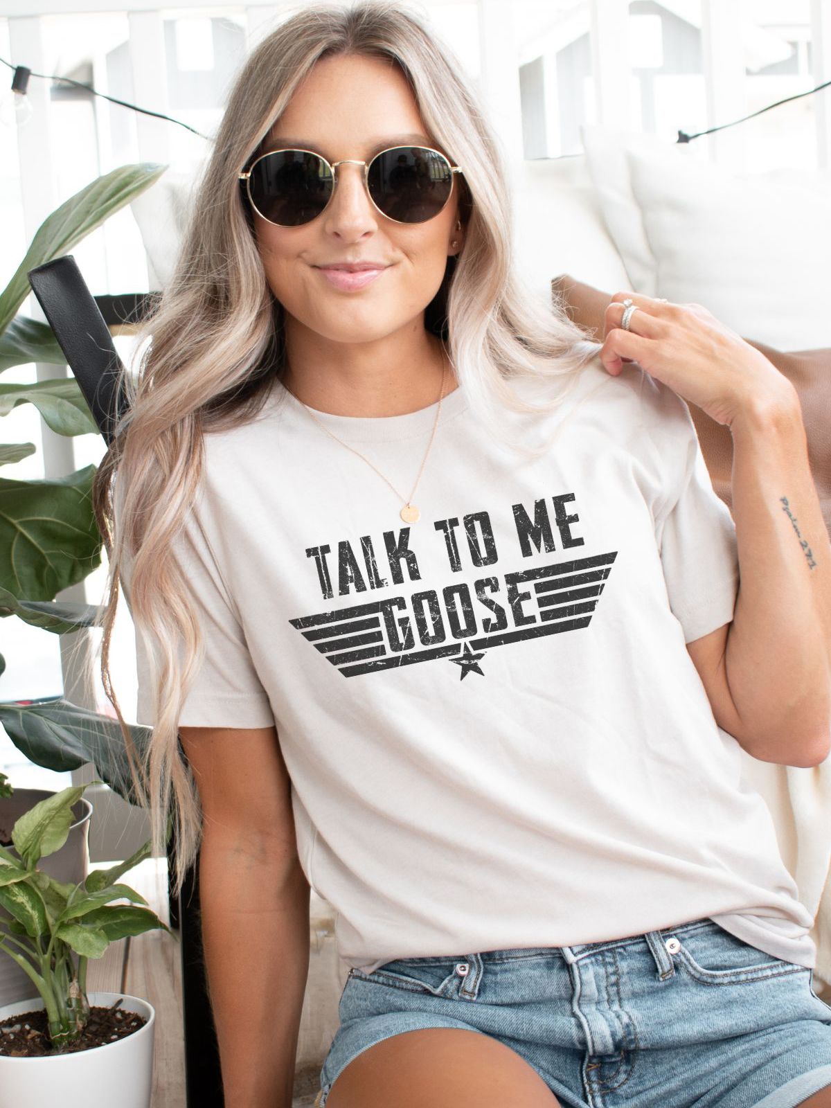 Woman wearing Talk to Me Goose t-shirt sitting casually