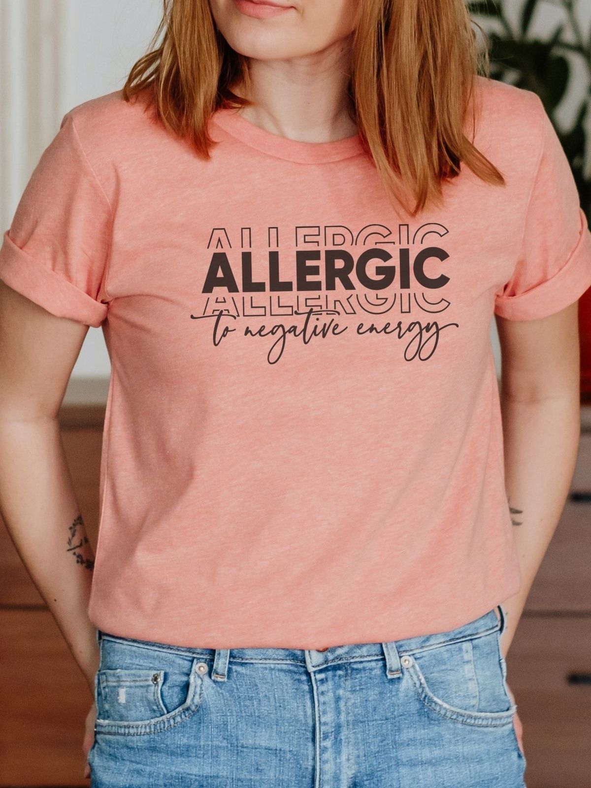 Woman wearing peach t-shirt with Allergic to Negative Energy text