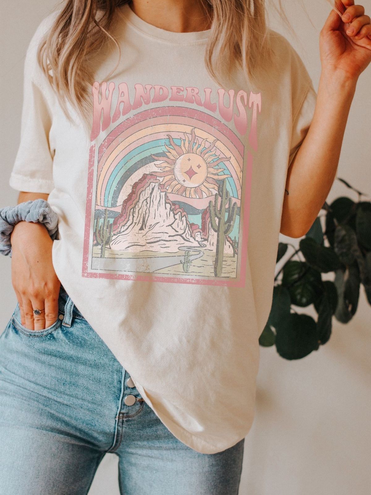 woman wearing a t-shirt with wanderlust design featuring a sun and mountains