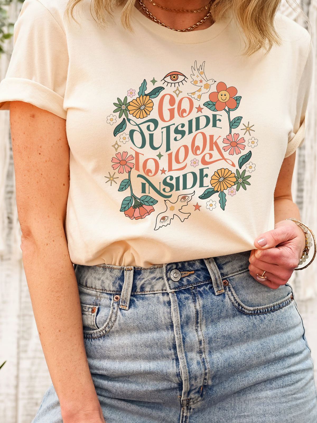 beige t-shirt with floral design and text 'Go Outside To Look Inside'