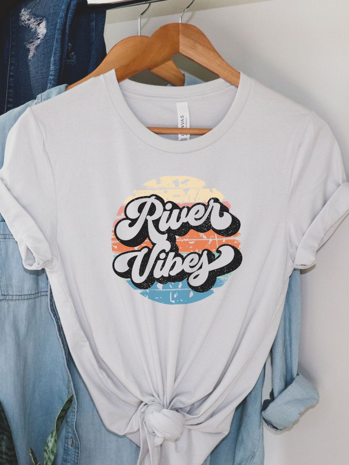 River Vibes t-shirt hanging on a wooden hanger