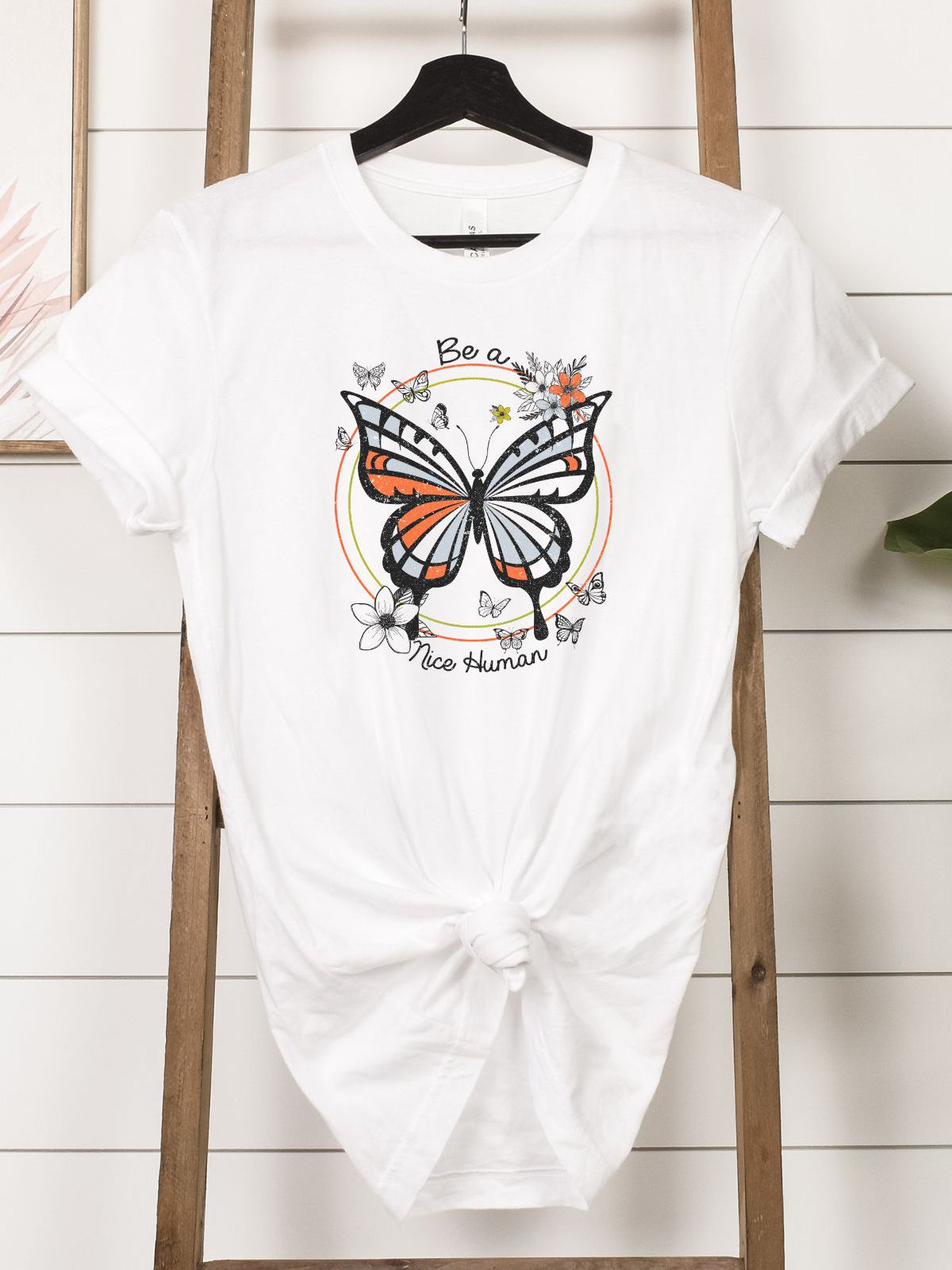 white t-shirt with butterfly design and Be a Nice Human text
