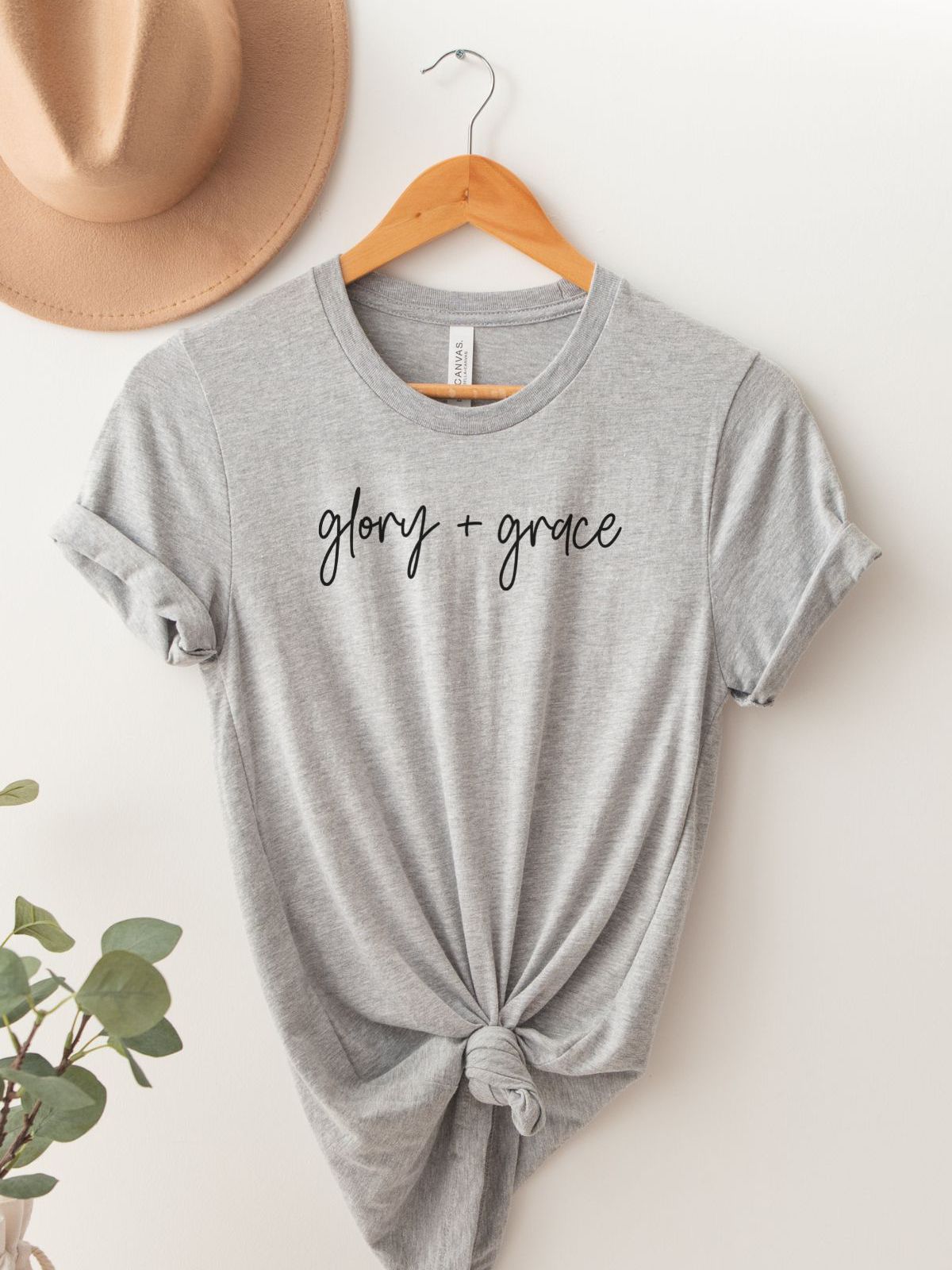 gray t-shirt with glory grace text on hanger with hat