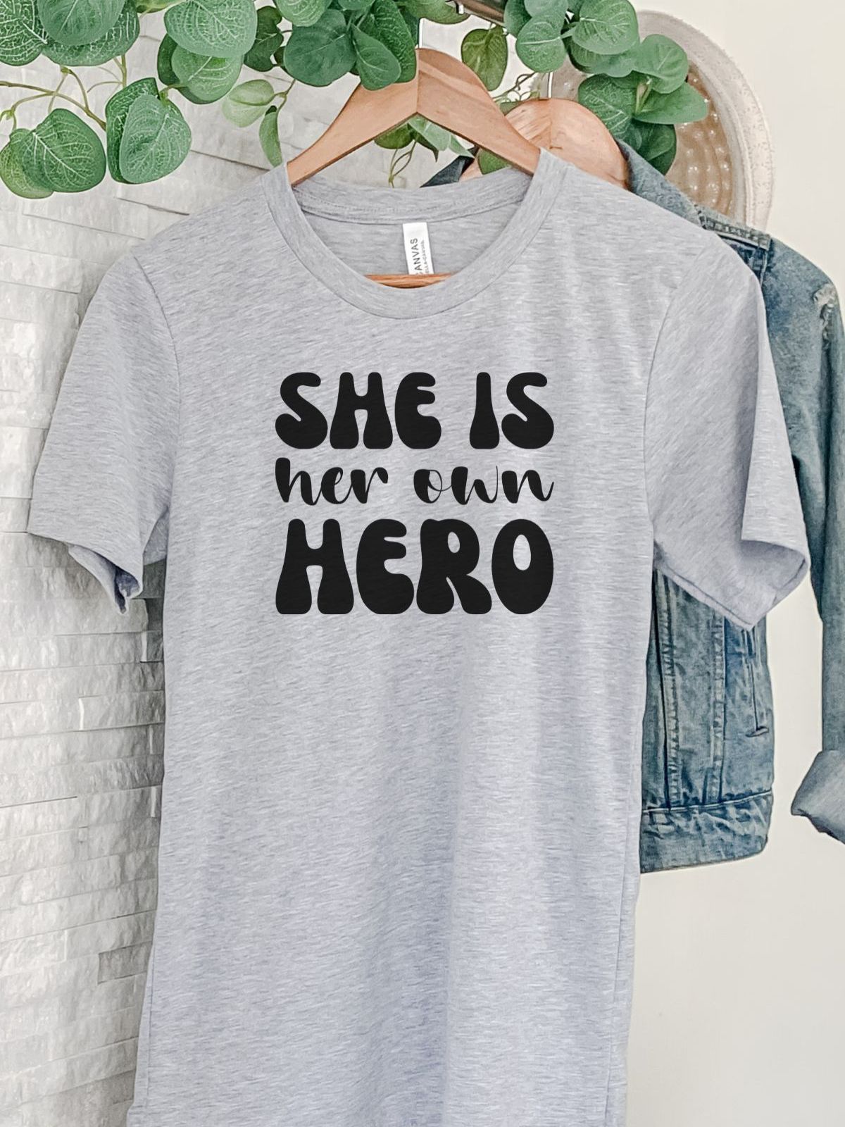 She Is Her Own Hero t-shirt hanging on a rack