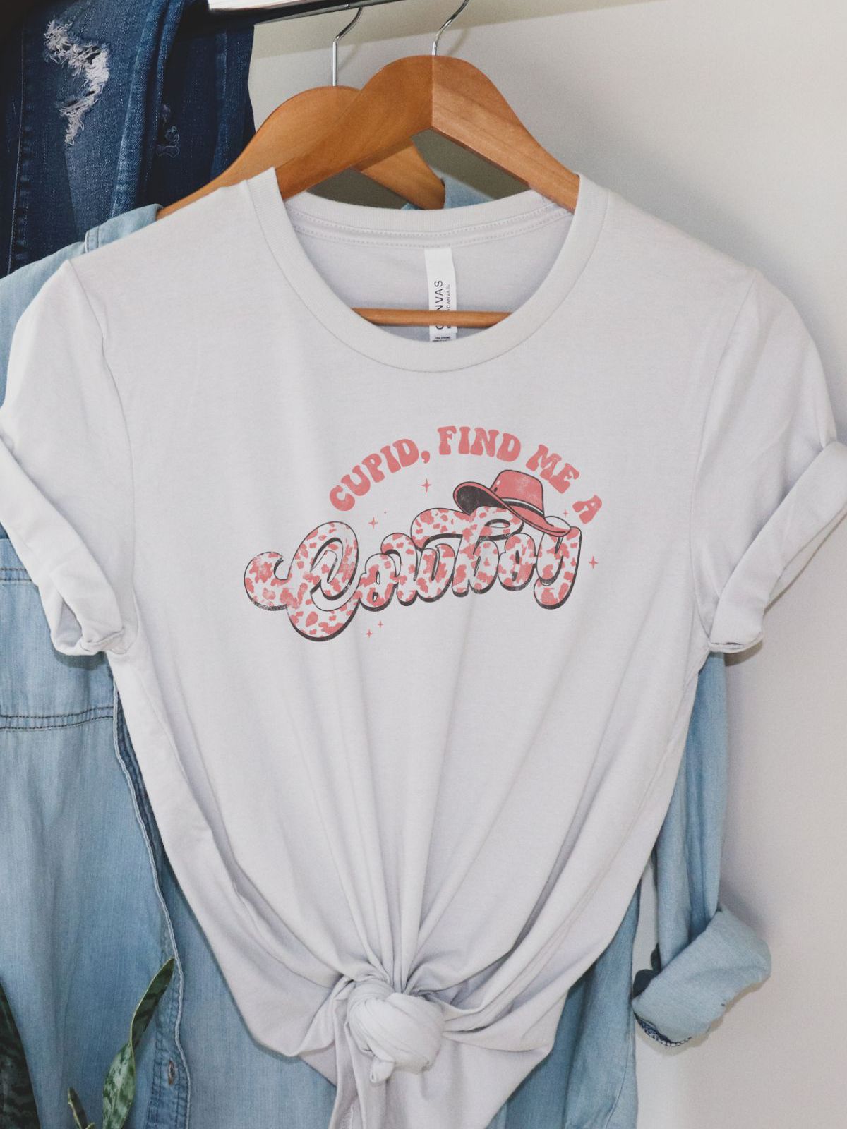 Cupid Find Me A Cowboy t-shirt hanging on a hanger