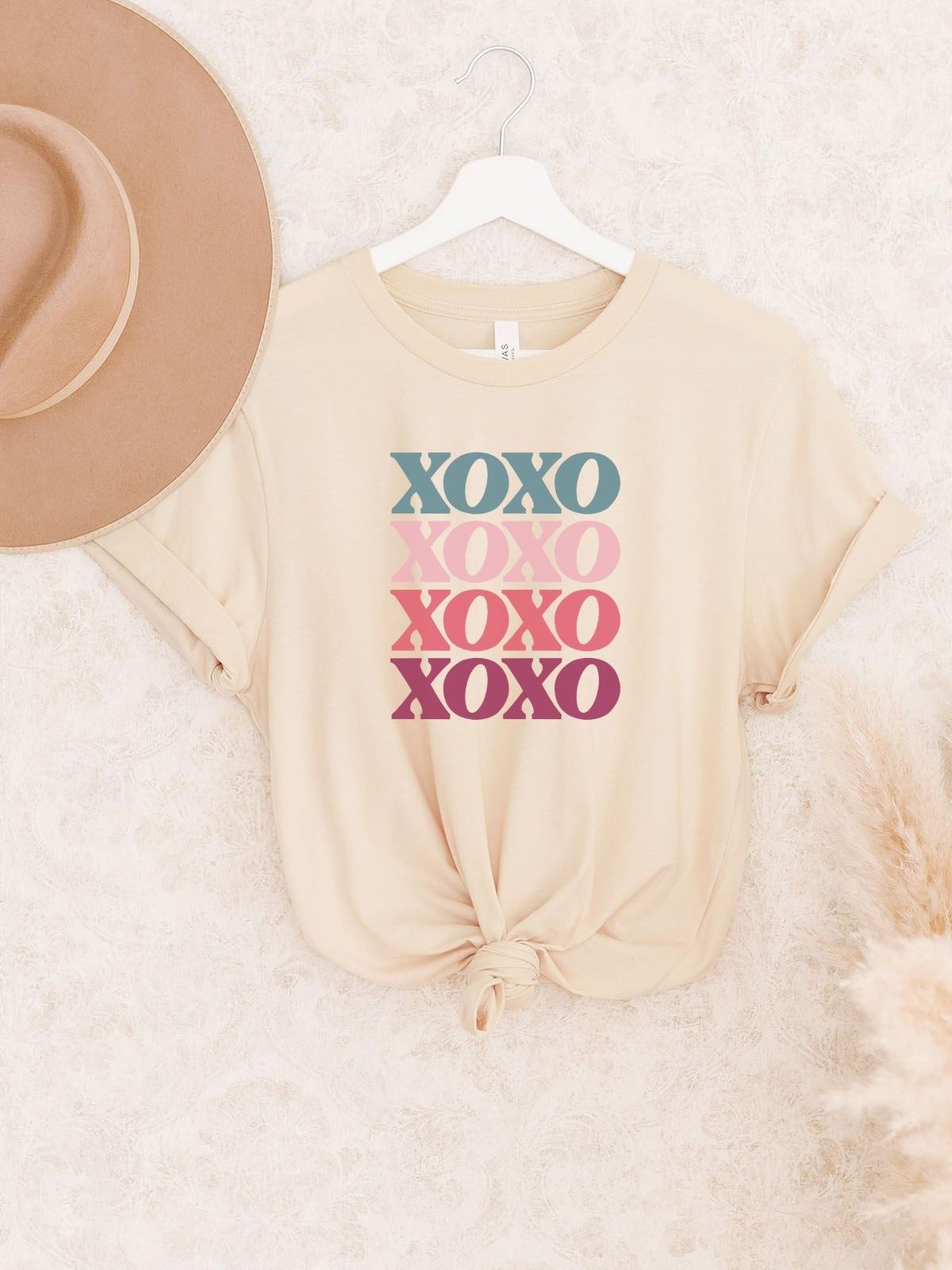 Beige XOXO graphic t-shirt on hanger with hat
