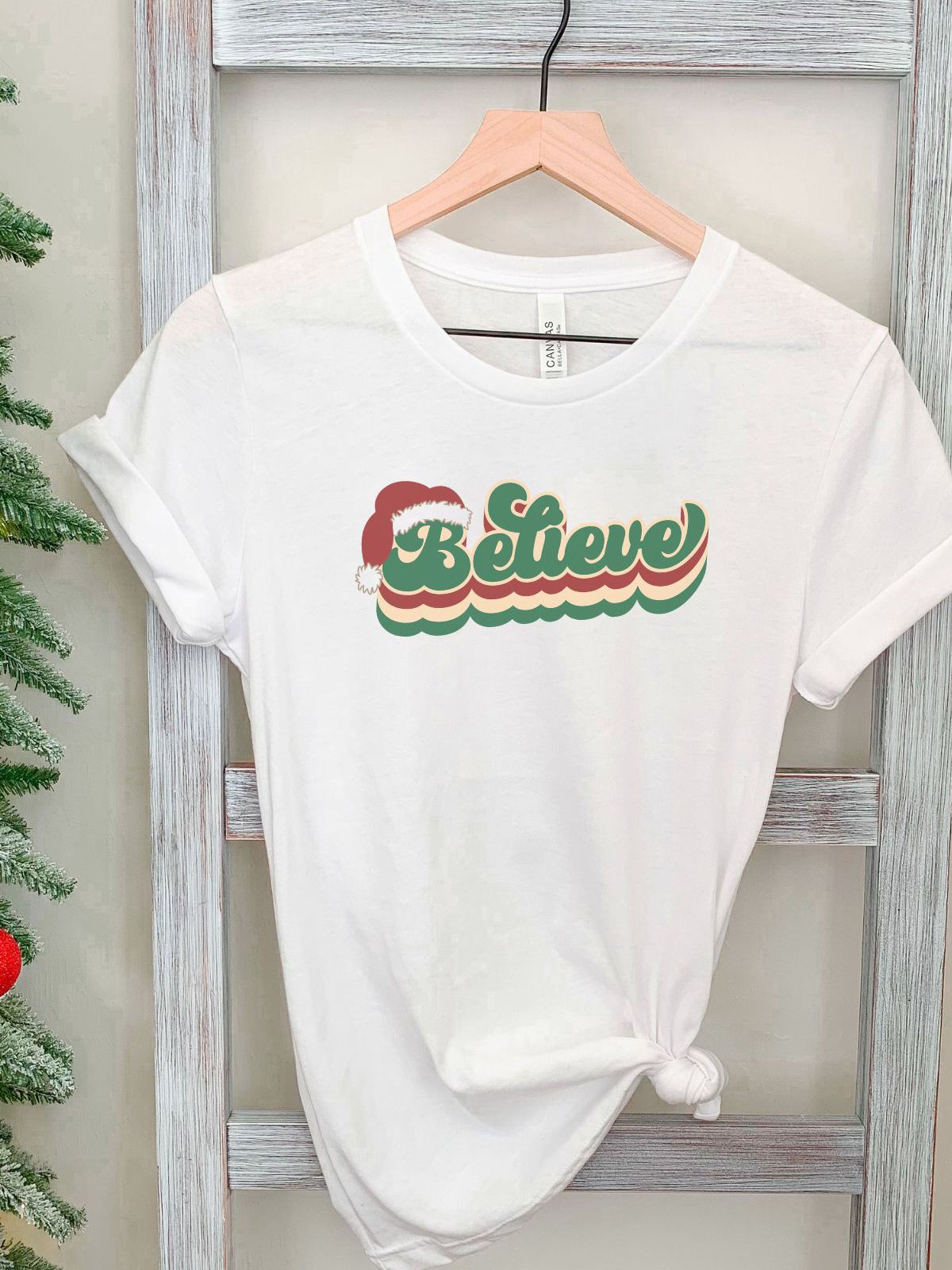 White t-shirt with Believe text and Santa hat design